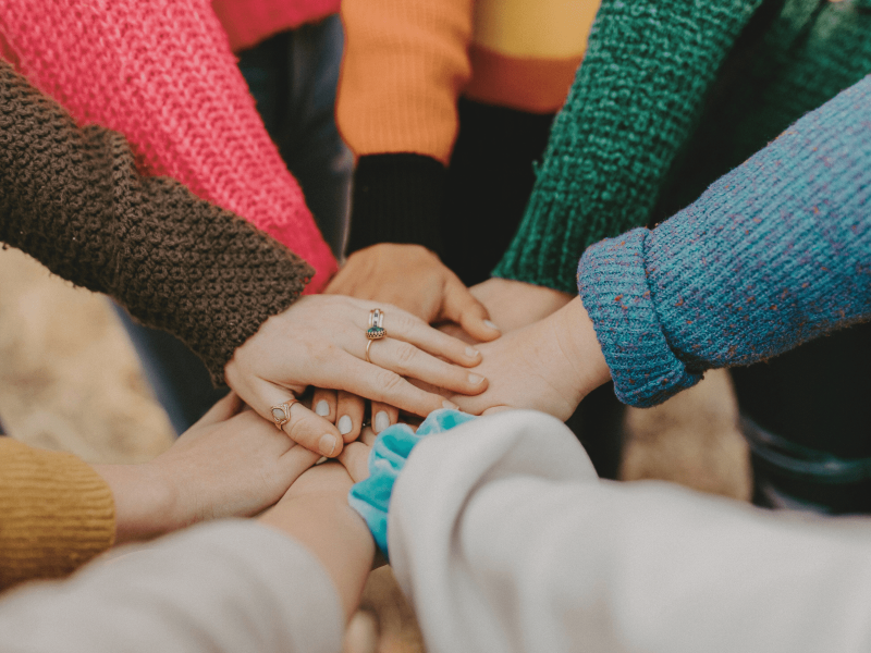 eine Gruppe von Schüler*innen legen ihre Hände aufeinander
